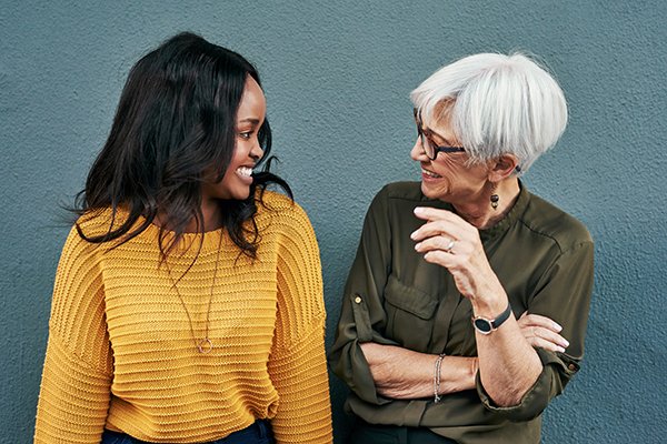 Young black woman and older Caucasian woman laugh and smile at each other