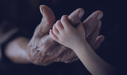 child's hand grips finger of elderly man