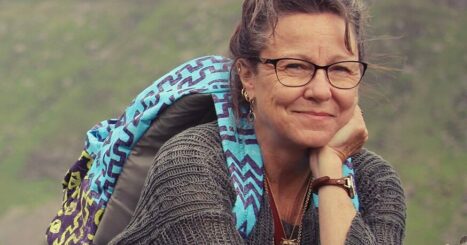 Colleen Harris leans on a rock while hiking