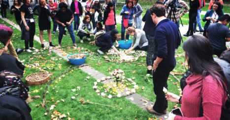 Young people spread leaves and petals in a memorial