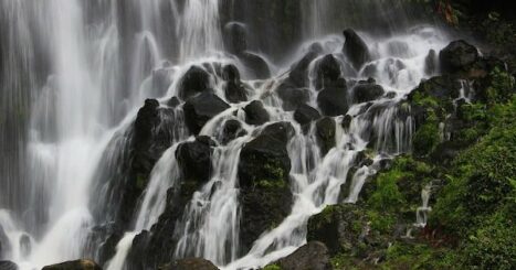 waterfall cascades over mossy boulders