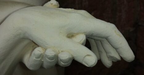 sculpture of one person's hand resting in another person's hand