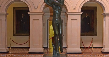 Statue of naked woman holding infant aloft in a museum